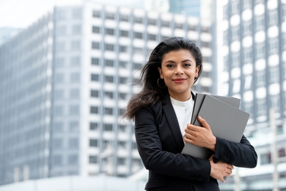 Woman holding folders in front of a bulding